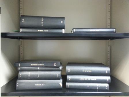 picture of a number of black-bound theses piled up in a cupboard over two shelves