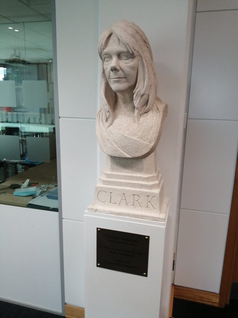 Image of a bust of Lady Clark of Calton, situated on a pedestal against a white wall. 