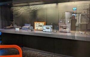 This image shows a large display case with several pieces of electrical recording equipment displayed in side. 