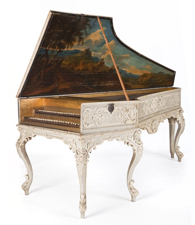 A white painted harpsichord. Inside the lid is a painted landscape.