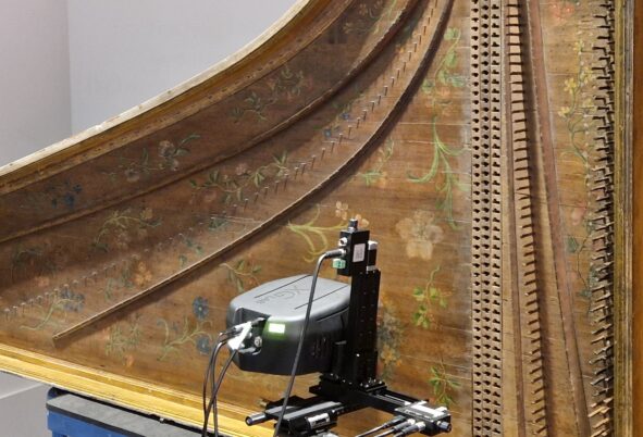 A expensive camera mounted taking images of the interior of the harpsichord. 
