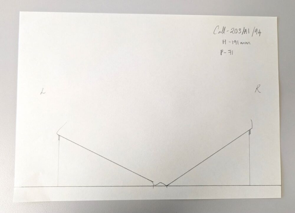A technical drawing on a sheet of paper. The drawing shows a book open, highlighting the angle at which the pages open.