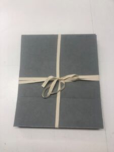 Grey folder wrapped in white string on a table.