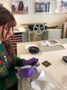 Blog writer sitting holding a glass plate negatives from the Royal Zoological Society of Scotland’s Archive