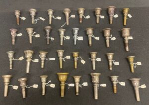 Brass mouthpieces organised nealty on top of a grey soft flat surface