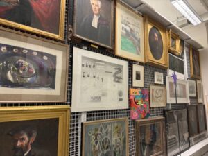 Lots of framed artworks of different sizes hanging on art racking