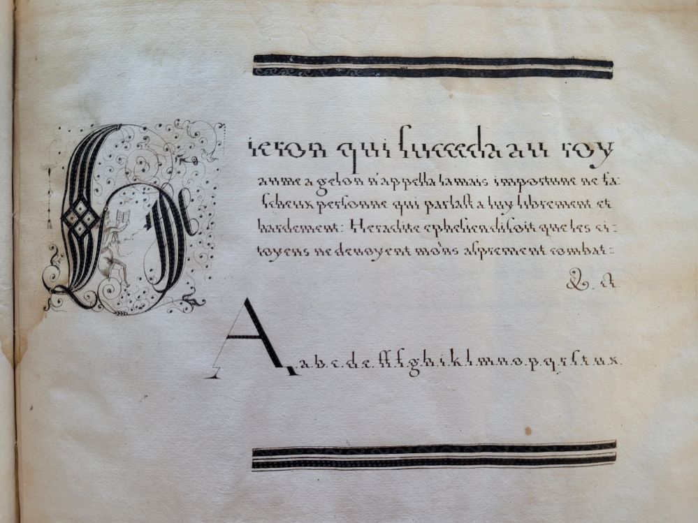 Calligraphy in black ink on white paper. The first initial, an ‘H’, is larger than the rest of the text and decorated with a picture of a man reading a book.