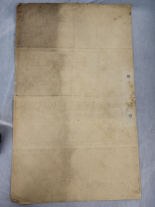 The backside of a foolscap sized page. A sharp vertical line shows where the page has been cleaned, and where the dirt remains.