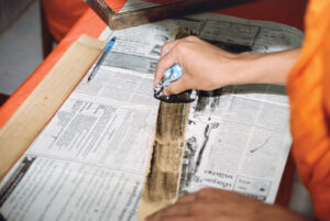 Ink is being wiped over the top of a palm leaf.