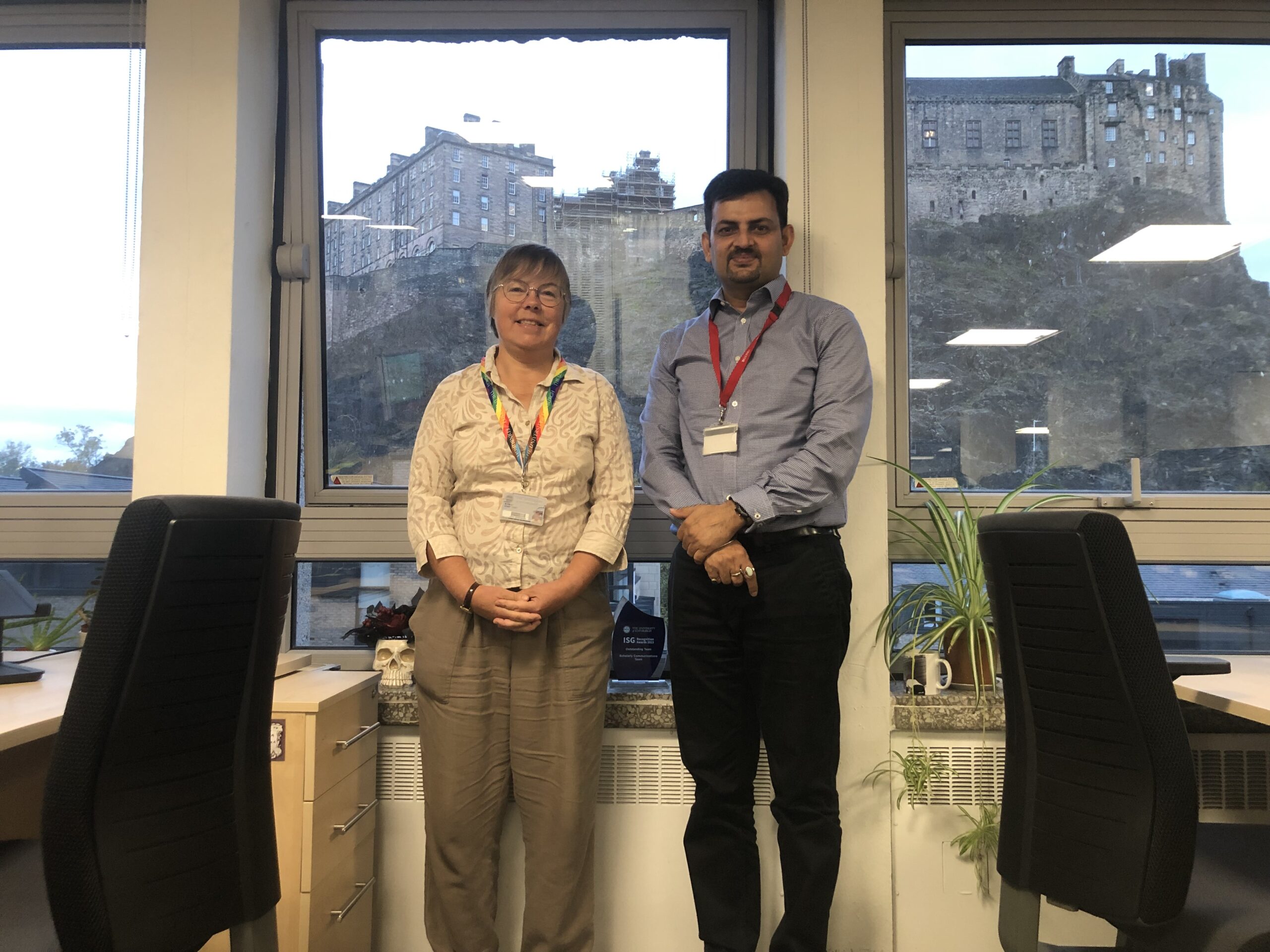 2 people in an office with Edinburgh Castle in the window.