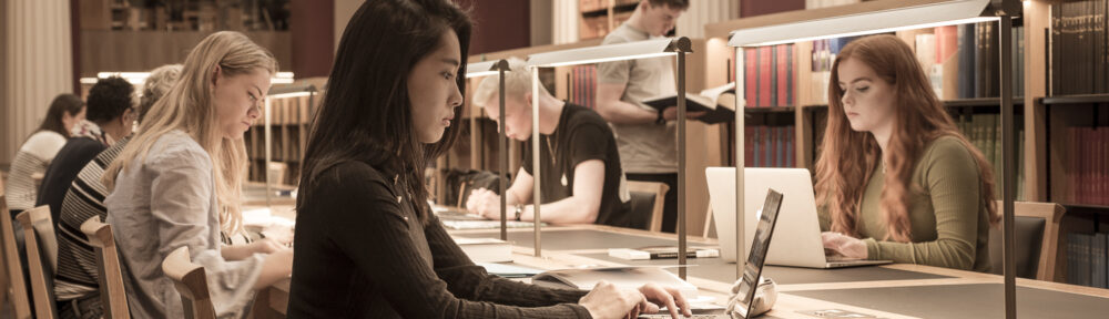 Image of students studying at desks in the Senate Room in the Law Library.