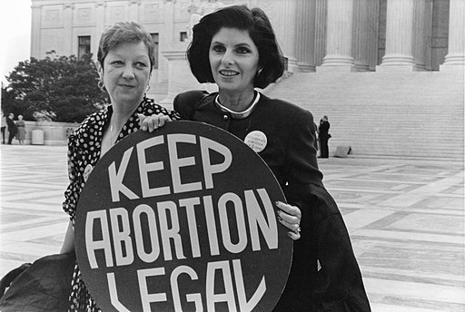A scanned photo of the original black and white photograph taken by Lorie Shaull at the Supreme Court. Norma McCorvey, left, who was Jane Roe in the 1973 Roe v. Wade case, stands with her attorney, Gloria Allred, outside the Supreme Court in April 1989. They hold a circular sign that says 'Keep Abortion Legal'.