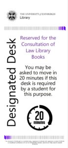 Designated Desk sign with Library branding. Sign reads: Reserved for the Consultation of Law Library Books You may be asked to move in 20 minutes if this desk is required by a student for this purpose.