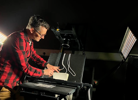 Project Photographer John Sikorski attends to the process of setting a Lyell Notebook into the digitisation camera. 